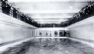 View of the swimming pool located in the basement of the '87 Gym, showing swimmers preparing to compete, and spectators watching from the gallery above