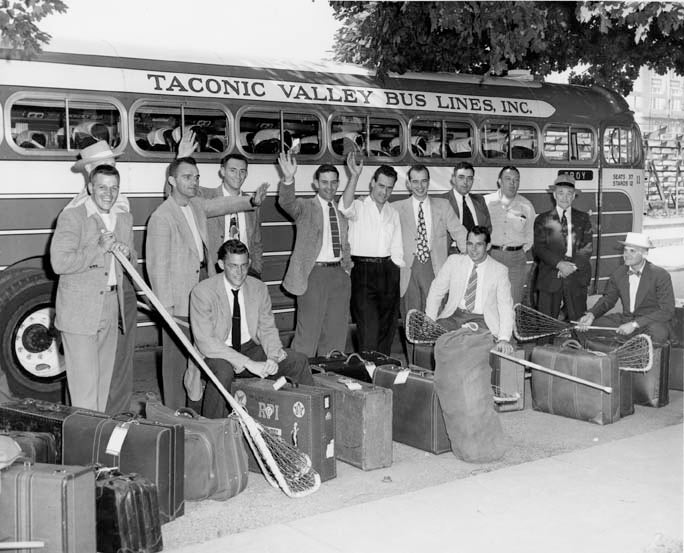 RPI Lacrosse team and coaches pose with sticks and luggage in front of a Taconic Valley Bus Lines bus enroute to New York to board a ship to London.